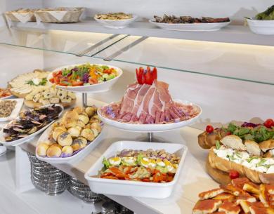 Buffet con salumi, verdure e pane assortito.