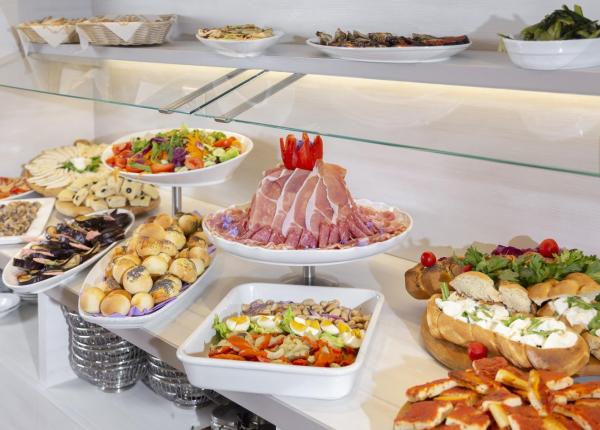 Buffet con salumi, verdure e pane assortito.