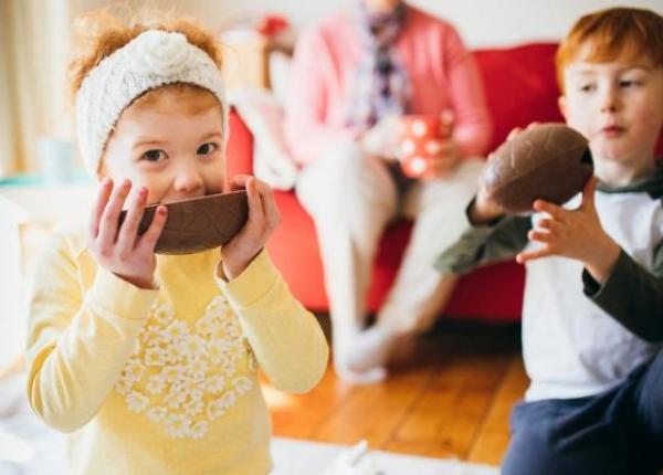 Bambini mangiano uova di cioccolato in soggiorno.